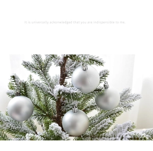 Bola de Navidad plateada mate colgada en una rama nevada para decoración festiva