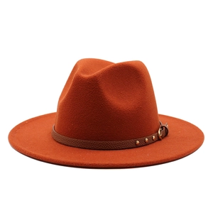 Detail of a rust-red wool fedora with a studded brown leather band and metal buckle