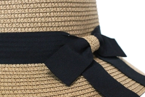 Gros plan sur la texture en paille tressée et le ruban noir du chapeau d'été