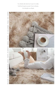 Plush beige shag rug texture with grey pom-pom throw blanket in cozy home setting