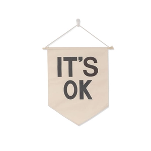 Detail of beige canvas wall banner with It's OK print and natural wooden pole hanging