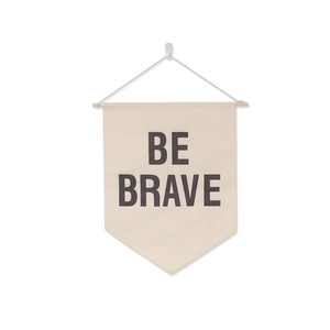 Detail of beige canvas wall banner with Be Brave text and a wooden hanging rod