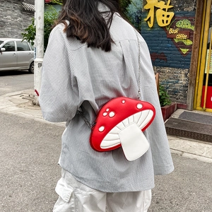 Detailed view of a cute red mushroom crossbody bag with white dots and a silver chain strap