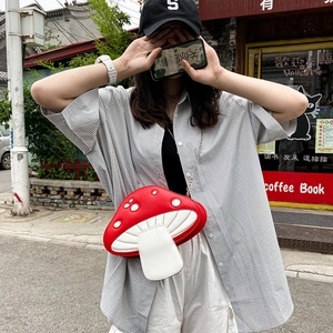 Detail of red mushroom crossbody bag with white polka dots and metal chain strap