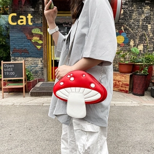 Detailed view of red mushroom crossbody bag with white dots and metal chain strap