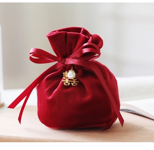 Detail of red velvet wedding candy bag with gold double joy charm and pearl decoration