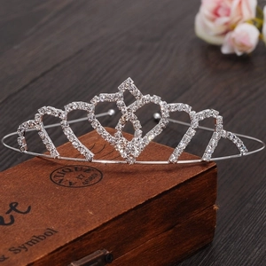 Detailed view of silver heart crown headband with white rhinestones on vintage wood box
