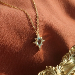 925 silver vintage gold star necklace with blue topaz pendant on orange textured fabric