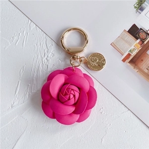 Detail of faux leather camellia flower keychain with gold coin charm and metal ring