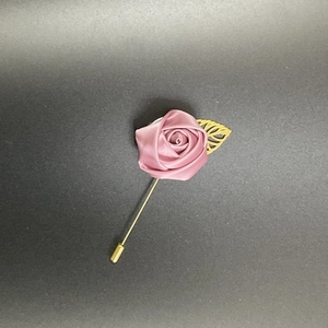Detail view of handmade dusty rose satin rose brooch with golden hollow leaf and long pin