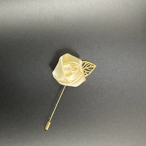 Detail of handmade cream satin rose lapel pin with a gold leaf on a long suit needle