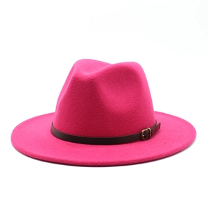 Detail of rose red wool fedora hat featuring a brown leather band and bronze buckle