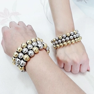Heavy layered gold and silver stainless steel beaded bracelet on a person's wrist