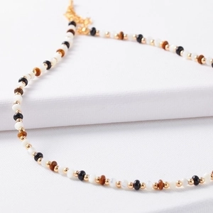 Retro beaded necklace with tiger eye stone and black agate beads on white fabric