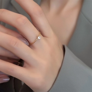 Close-up of minimalist 18k gold-plated titanium steel ring with a single zircon on finger