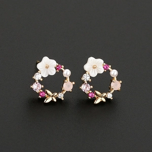 Close-up of pearl flower earrings with butterfly details and colorful zircon stones