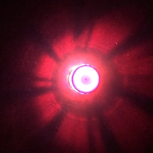 Close-up of circular LED spinning toy showing red light beams in a dark environment