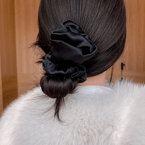 Elegant black silk scrunchie worn on a messy bun with a soft vintage glossy texture