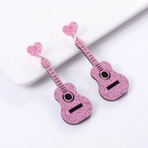 Macro detail of pink glitter guitar earrings with heart-shaped studs on white surface