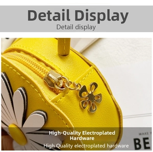 Close-up of golden metal zipper and flower pendant on yellow daisy crossbody bag