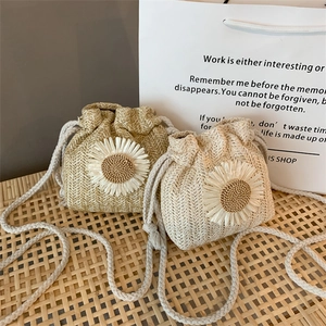 Close-up of woven straw bucket bags with sunflower accents and cotton drawstring straps