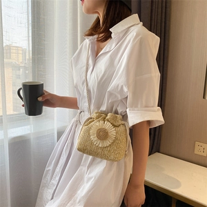 Detail of hand-woven straw bucket bag with white daisy decor and drawstring