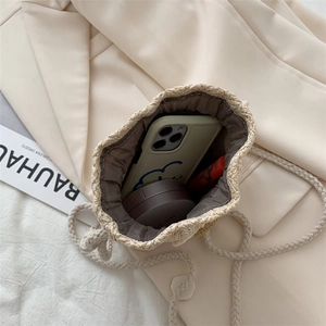 Minimalist straw bucket bag with cotton drawstring closure showing inner storage space
