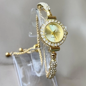 Close-up of golden quartz watch with sparkling rhinestones on the bezel and snake-style band