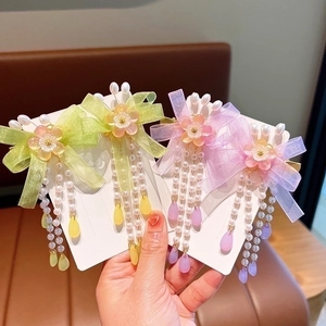 Close-up of girls butterfly hair clips with yellow and purple tassels and pearl beads