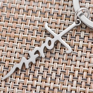 Polished stainless steel keychain with faith cross pendant on a textured background