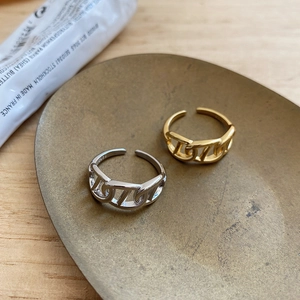 Macro shot of silver and gold thick chain rings with S925 hallmark on a brass tray