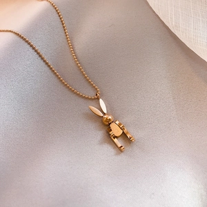 Close-up of golden rabbit pendant with Luck engraving on soft pink silk fabric background