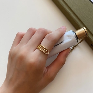 Minimalist 18K gold chain link ring shown on finger with aesthetic background props