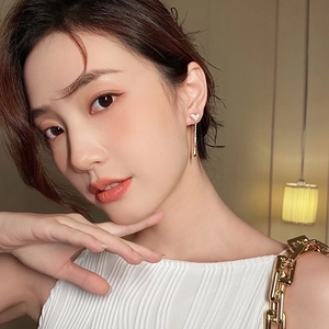Elegant gold heart tassel earrings with sparkling crystals shown worn on ear for women