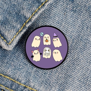 Close-up of cute cartoon ghost pins with BOO text on blue denim fabric background