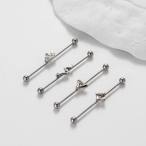 Detail view of 1.2mm industrial barbells featuring crown, snake, and triangle motifs