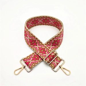 Close-up of pink geometric ethnic style woven strap with gold metal hooks and buckle
