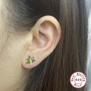 Elegant 925 sterling silver leaf stud earrings with green stones on a female model