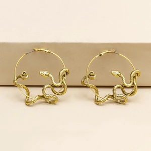 Exaggerated gold snake-shaped hoop earrings with textured scale finish on beige background