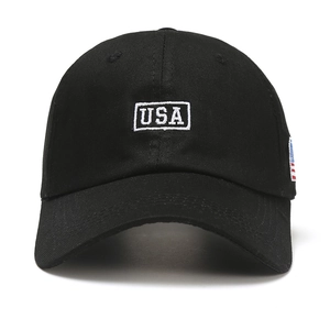 Black baseball cap featuring white USA embroidery and US flag patch on a white background