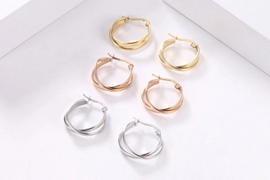 Dettaglio di orecchini a doppio cerchio intrecciato nei colori oro, argento e oro rosa