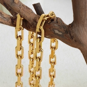 Chunky 18K gold plated Cuban link chain necklace displayed on a natural tree branch