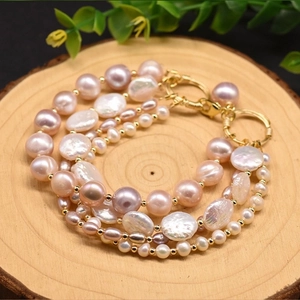 Close-up of pink and white baroque pearls on a wooden tray with gold metal accents