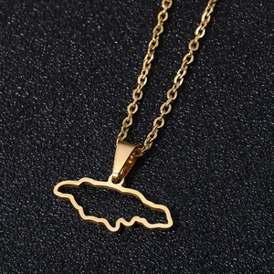 Macro shot of gold hollow Jamaica map pendant on O-chain against black texture background