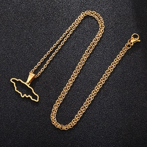Detailed view of the gold-tone Jamaica map pendant on a chain over a black textured surface