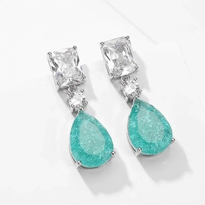 Detail of pear-shaped cyan gemstones with crackle texture on silver dangle earrings