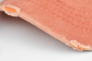 Vue macro de la visière de casquette orange délavée avec trous et surpiqûres