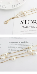 Detail view of elegant multi-layered golden bead chain with white pearls and lobster clasp