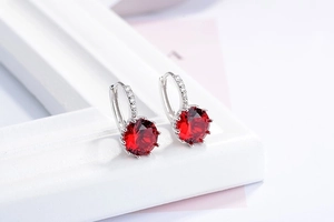 Detail of red round-cut ruby huggie earrings with white zircon accents in silver