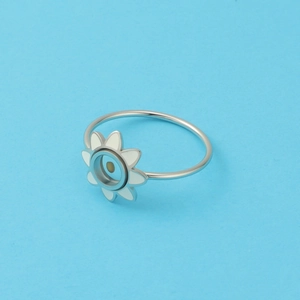 Detailed close-up of a silver sunflower ring with white enamel petals on blue background